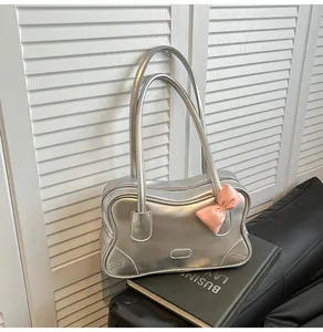 Close-up of metallic silver tote bag with a pink bow decoration on a black sofa