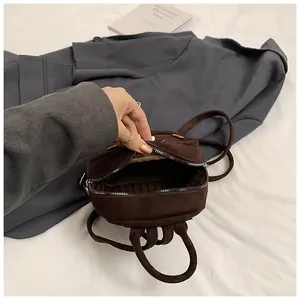 Detail view of the deep brown suede backpack showing interior striped lining and zipper