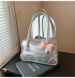Detail of silver metallic tote bag featuring a pink bow and zip closure on black book