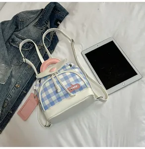 Detail of blue plaid mini backpack with apple embroidery and pink leather handle