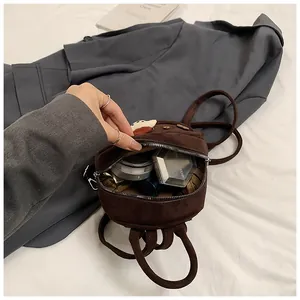 Detail of coffee brown suede mini backpack showing internal storage for cosmetics