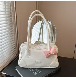Close-up of a white tote bag with a pink leather bow detail and zipper closure