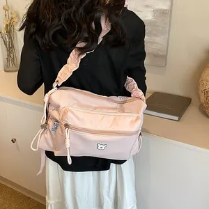 Sac bandoulière en nylon rose avec bandoulière à volants et patch ours sur mannequin