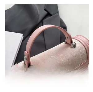 Detailed close-up of pink silk jacquard fabric and metal lock on this stylish handbag