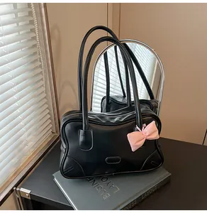 Detail of black faux leather tote bag with pink satin bow and oval metal hardware