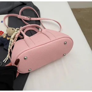 Detail of pink lychee leather bucket bag showing silver bottom studs and bear charm