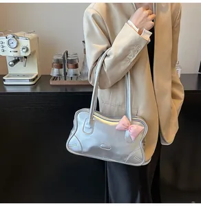 Silver metallic wave shoulder bag with pink bow detail shown on shoulder of a beige blazer