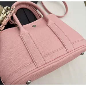 Detail shot of pink pebble leather texture and metal protective feet on bucket bag base