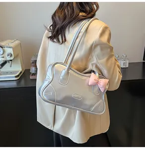 Detail of silver metallic tote bag featuring a decorative pink 3D bow and slim shoulder straps