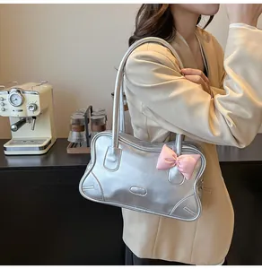 Detail of silver metallic tote bag with pink bow accessory on model in cafe setting