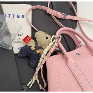 Detail of light pink pebble leather bucket bag with cute teddy bear charm pendant