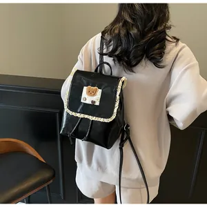 Detail eines schwarzen PU-Lederrucksacks mit zarter Spitze und Plüschbären-Stickerei