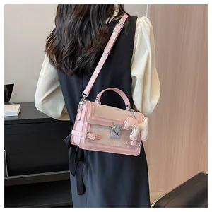 Detail of pink crossbody bag with a butterfly lock, puppy charm, and textured floral fabric