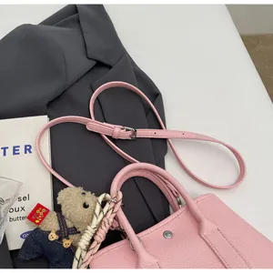 Detailed macro view of pink pebbled leather bucket bag with silver studs and teddy charm