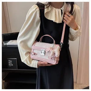 Detail of pink leather and lace crossbody bag with butterfly clasp and dog pendant