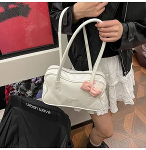 Detail of white PU leather tote bag featuring a pink silk bow and long shoulder straps