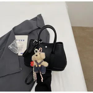 Detail of black lychee grain leather bucket bag with a cute bear charm for daily commute