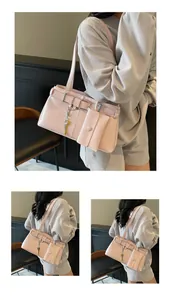 Detail view of pink motorcycle shoulder bag with buckle strap and mini pendant