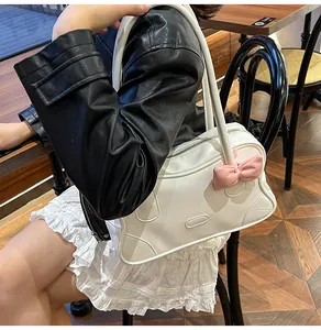 Macro shot of white tote bag with pink bow pendant on female model in a cafe setting