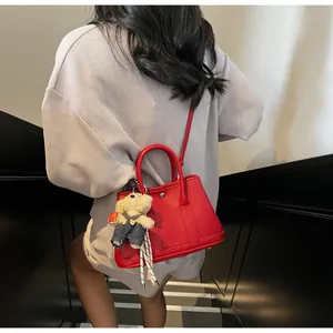 Detail of red lychee leather bucket bag with white bear pendant shown in a lifestyle setting