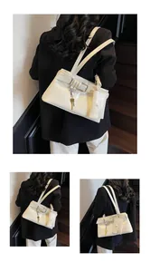 Detail of cream shoulder bag featuring decorative buckles and gold key charm accessories