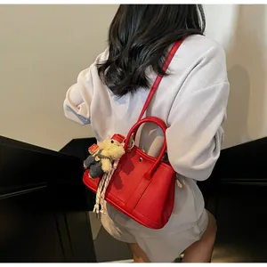 Detail of red pebble leather bucket bag with scarf and bear charm on a model