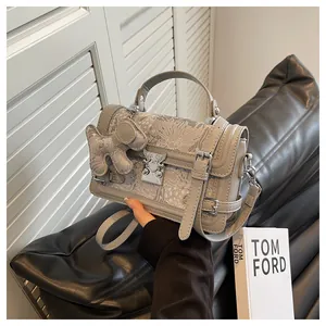 Detail of grey crossbody bag with traditional embroidery and silver metal clasp