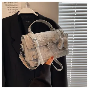 Detail view of silver crossbody bag with heart buckle and dog charm on suit background