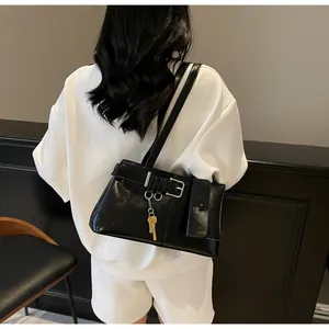 Detailed view of black glossy shoulder bag with silver buckle and metal key accessory