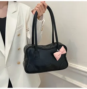 Detail of a black tote bag with a pink 3D bow and long shoulder straps for women