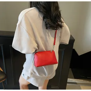 Close-up of a red litchi texture crossbody bag worn with a grey waffle leisure outfit