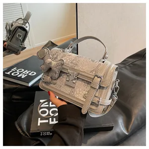 Detail of gray jacquard crossbody bag with silver lock and decorative bear charm