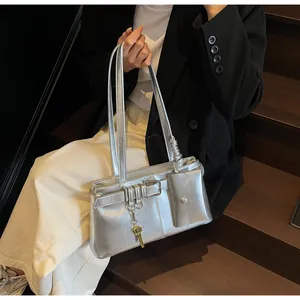Detailed shot of silver metallic shoulder bag with mini pouch and gold key pendant