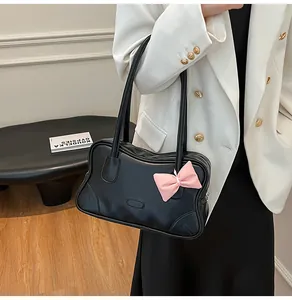 Detail of black glossy tote bag with wavy edges and a pink bow on a white suit model