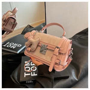 Close-up of pink leather handbag with teddy bear charm and silver heart buckle detail