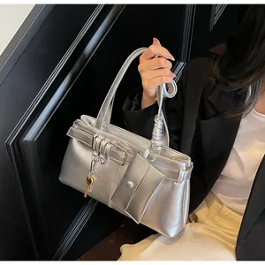 Detail of silver metallic shoulder bag with mini pouch and key charm on model
