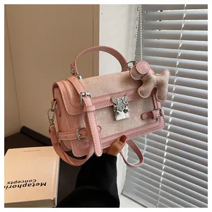 Detail of pink leather handbag with heart buckle, jacquard fabric, and plush dog charm