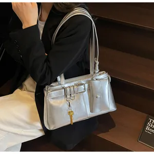 Detailed view of silver metallic shoulder bag with belt buckles and key charm detail