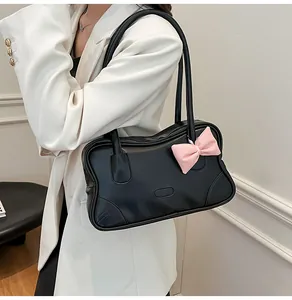Detail of black faux leather tote bag with large pink bow shown on model's shoulder