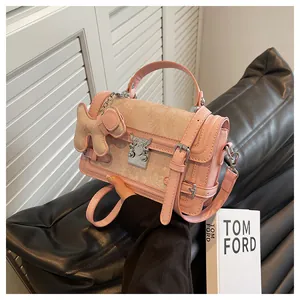Detail of pink leather handbag with beige jacquard flap and cute dog plush charm