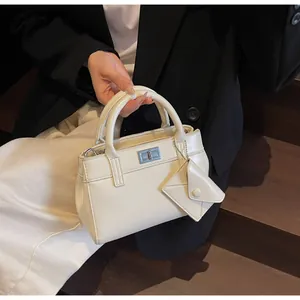 Detail of cream white trapezoidal handbag with silver clasp and mini envelope pouch