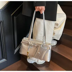 Detail of metallic silver shoulder bag with buckle straps and golden key charm
