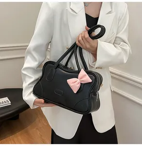 Detail of black tote bag with pink bow accent and stylish wavy edge design