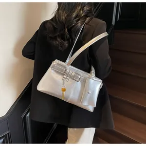 Detail of silver metallic shoulder bag with side pouch and key charm on model