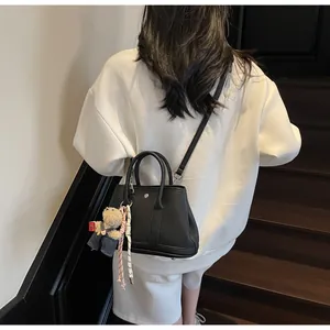 Detail of black pebbled leather bucket bag with cute bear charm and woven keychain