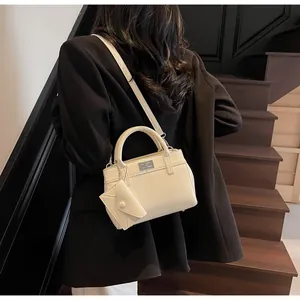 Detail of off-white leather handbag with silver twist lock and mini envelope pouch