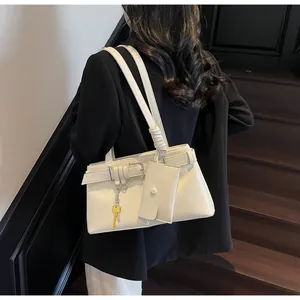 Detail of white rectangle shoulder bag with buckle strap, gold key charm and mini pouch