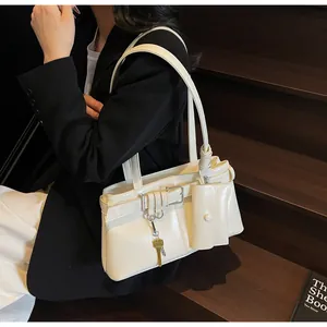 Detail of a chic cream-white shoulder bag with glossy patent finish and mini pouch accessory