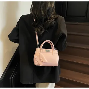 Pink patent leather handbag with mini pouch and gold buckle shown on a model