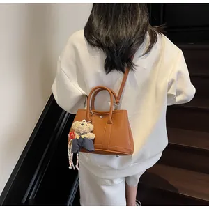 Brown lychee leather bucket bag with cute bear charm shown on indoor stairs
